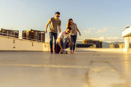 Friends having fun with skateboard on rooftop of the buildingの写真素材