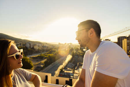 Sweet couple enjoying in a view of the city from balcony on sunset