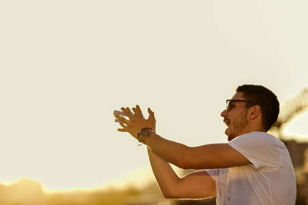 Handsome man on sunset is catching water bottleの写真素材