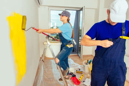 Couple renovate their living room from white to yellow with paint stick rollerの写真素材