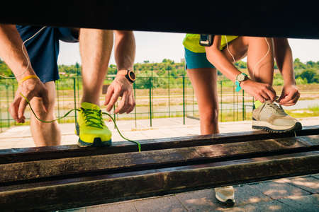 Fit couple tying their shoes and getting ready for running on riverside