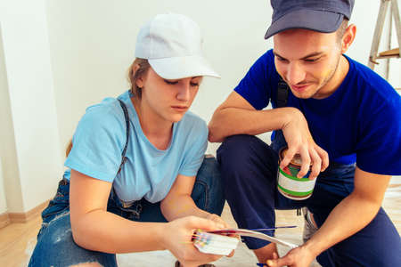 Cute girl holding color guide while choosing true color with her husband