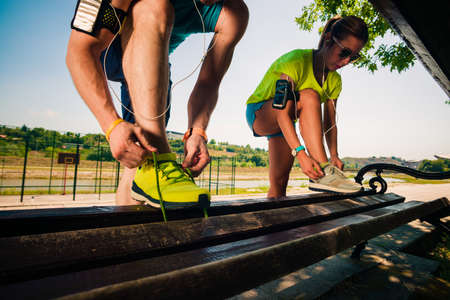 Fit couple tying their shoes and getting ready for running on riversideの写真素材