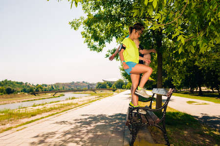 Athletic young couple doing stretching legs exercises together on the benchの写真素材