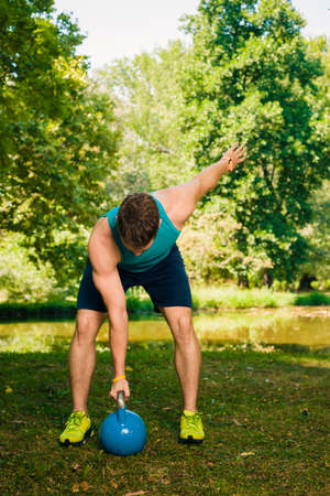 Fitness trainer training at park with kettlebellの写真素材