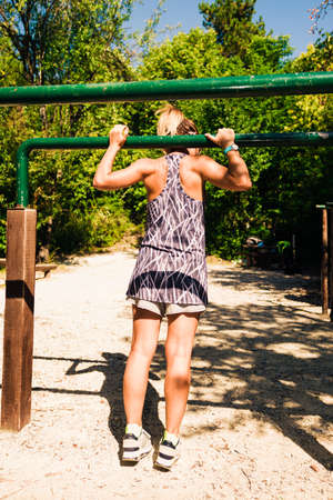 Female instructor workout on chin-up bar in forest gym
