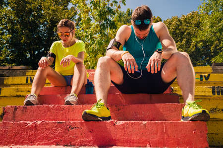 Healthy couple with headphones rest after running