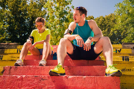 Healthy couple with headphones rest after runningの写真素材