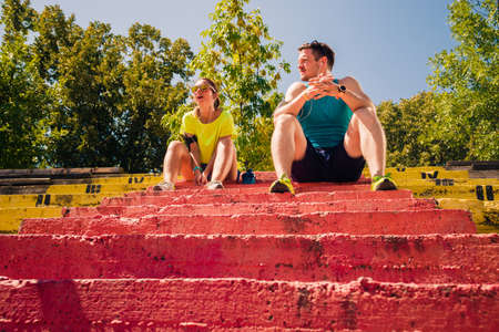 Runners in the city park resting after jogging and listening to musicの写真素材