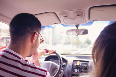 Happy Young Couple Driving in a Car in the city on a sunny day