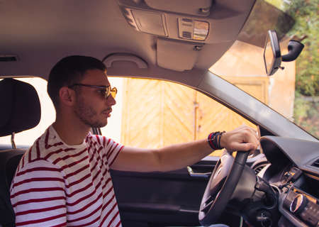 Handsome young Man parking the car in the garage on a sunny day