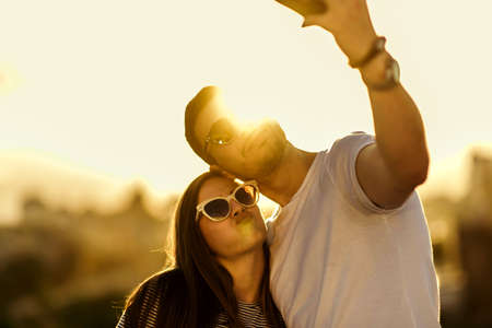 Attractive couple doing selfie with cellphone on sunset