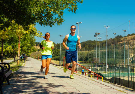 Shot of young man and woman running through the riverside trackの写真素材