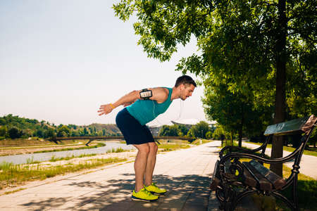 Motivated man warming up before jogging near the parkの写真素材