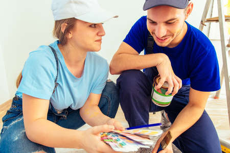 Girl in blue overall choosing color from palette for the walls with her husbandの写真素材