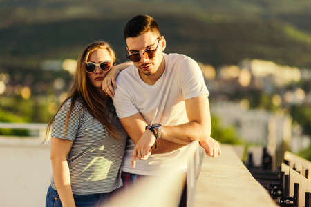 Sweet couple enjoying in a view of the city from balcony on sunsetの写真素材