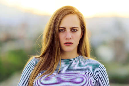 Outdoor photo of beautiful young woman standing faraway on the roof above the cityの写真素材