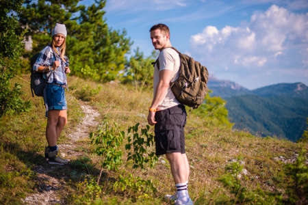 Enjoying the view in the mountain and taking photographs. Young couple at the summit enjoying the view.の写真素材