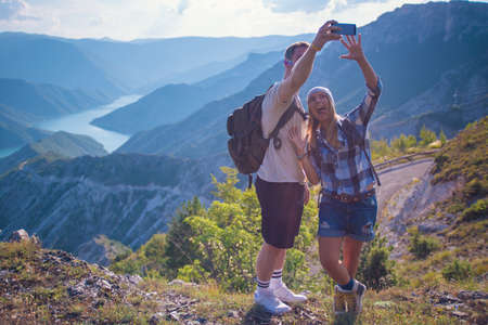 Breathing the fresh mountain air. Young couple making selfie while hiking in the mountain in the summer. Hiking concept in the mountain in summerの写真素材