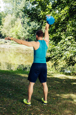 Fitness man doing kettlebell swing exercise in the parkの写真素材