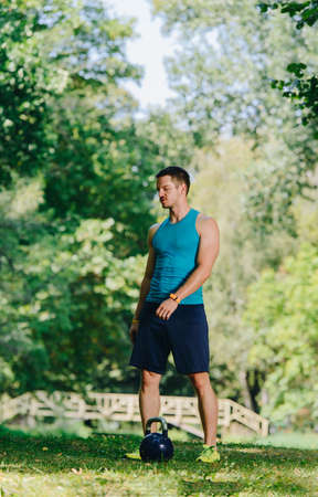 Young sportive man lifting kettlebell in the parkの写真素材