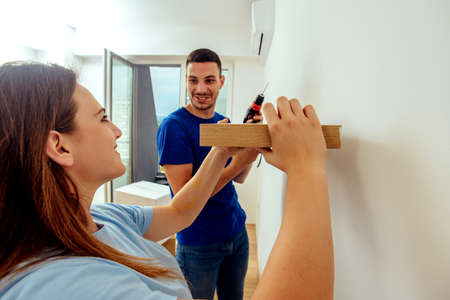 Married couple putting together shlef on the wall in their living roomの写真素材