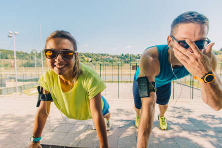 Running couple stretching and warming up in park before trainingの写真素材