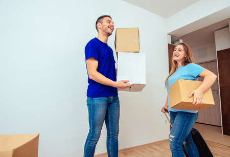 Man and young woman carrying box in their new houseの写真素材