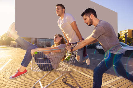 Full length portrait of a young man pushing a woman in a shopping cartの写真素材