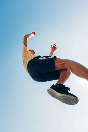 Adult guy doing parkour below blue skyの写真素材