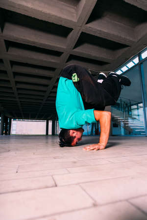 Young man doing headstand while trains parkourの写真素材