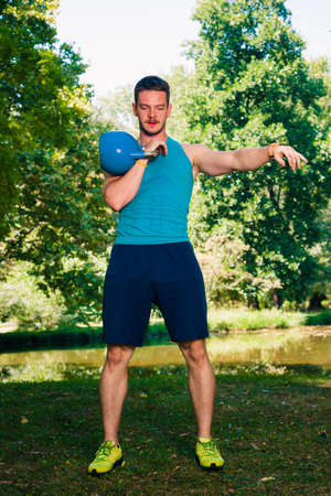 Fitness man doing kettlebell swing exercise in natureの写真素材