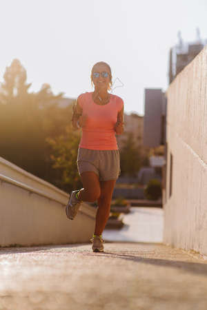 Fit girl running through the center at sunsetの写真素材