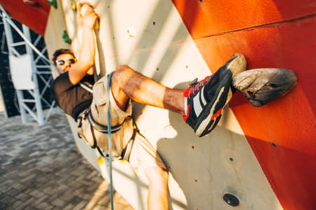 Young climber guy climbing on practical rock in climbing center, boulderingの写真素材