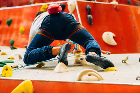 Man wearing belaying rope, climbing on a very high rock climbing wallの写真素材