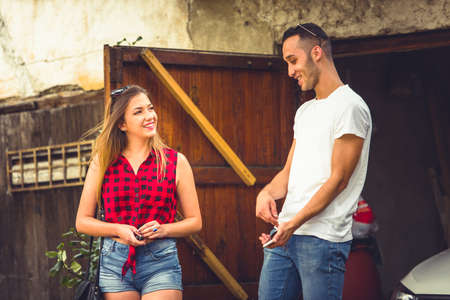 A guy and a girl standing outside, talking, smiling and looking happyの写真素材