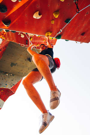 Young climber guy climbing on practical rock in climbing center, boulderingの写真素材