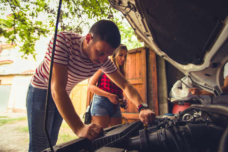 Guy looking worried fixing car problem with a girl next to himの写真素材