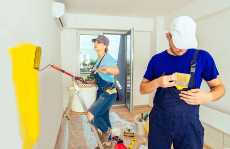 Couple renovate their living room from white to yellow with paint stick rollerの写真素材
