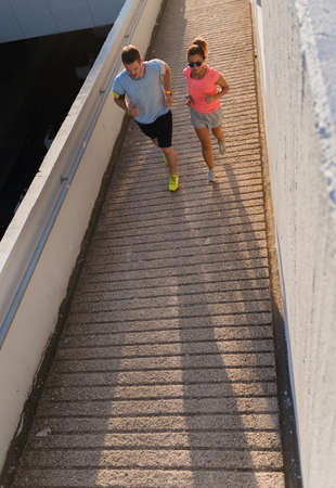 Sportive couple listening music while jogging through the city centerの写真素材