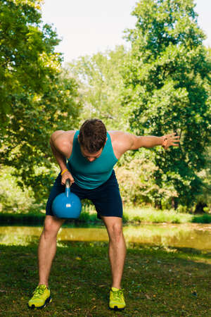 Fitness trainer training at park with kettlebellの写真素材