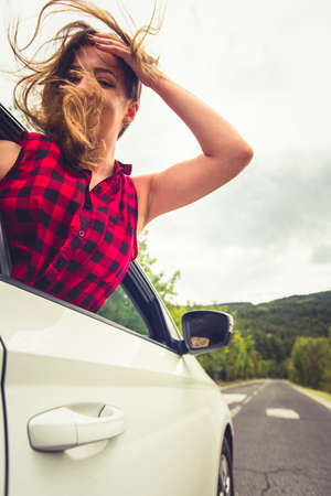 A girl is looking interested in the back seat in a car while someone is driving her in some rocky landscapesの写真素材