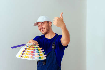 Man in blue uniform holding color palette for painting the wallsの写真素材