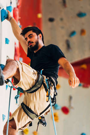 Young sporty man is bouldering in a climbing hallの写真素材