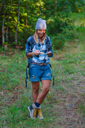 Young woman walking alone in the woods holding a map. Hiking concept in the mountain in summerの写真素材