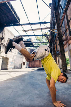 Sporty man maintains a balance on the ground with one handの写真素材