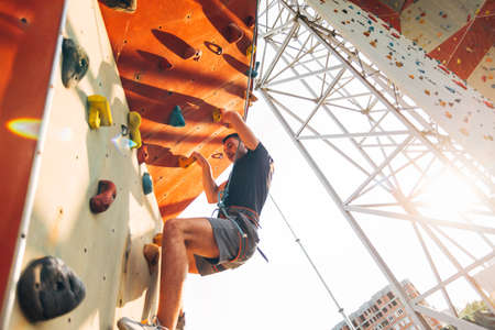 Young man climbs up an outdoors rock wallの写真素材