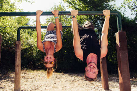 Strong man and athletic woman doing fitness and sport exercise in outdoor gymの写真素材