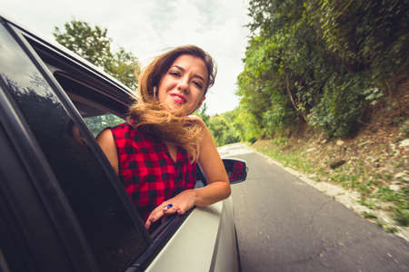 Woman is having fun in a car drive, enjoying a cloudy day and a beautiful natureの写真素材