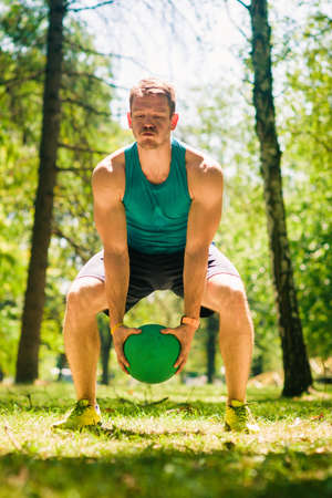 Fitness guy playing with medecine ball on grss in natureの写真素材
